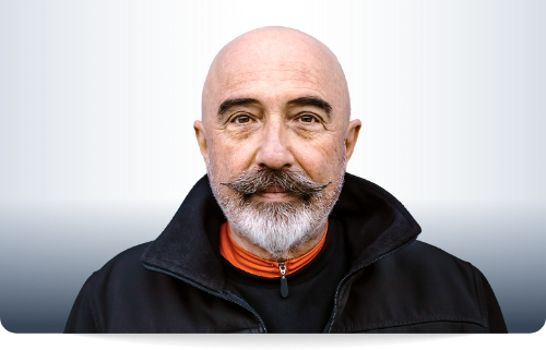 Ein 59 jahre alter Mann mit Glatze, Vollbart und einem schwarzen Hoddie.